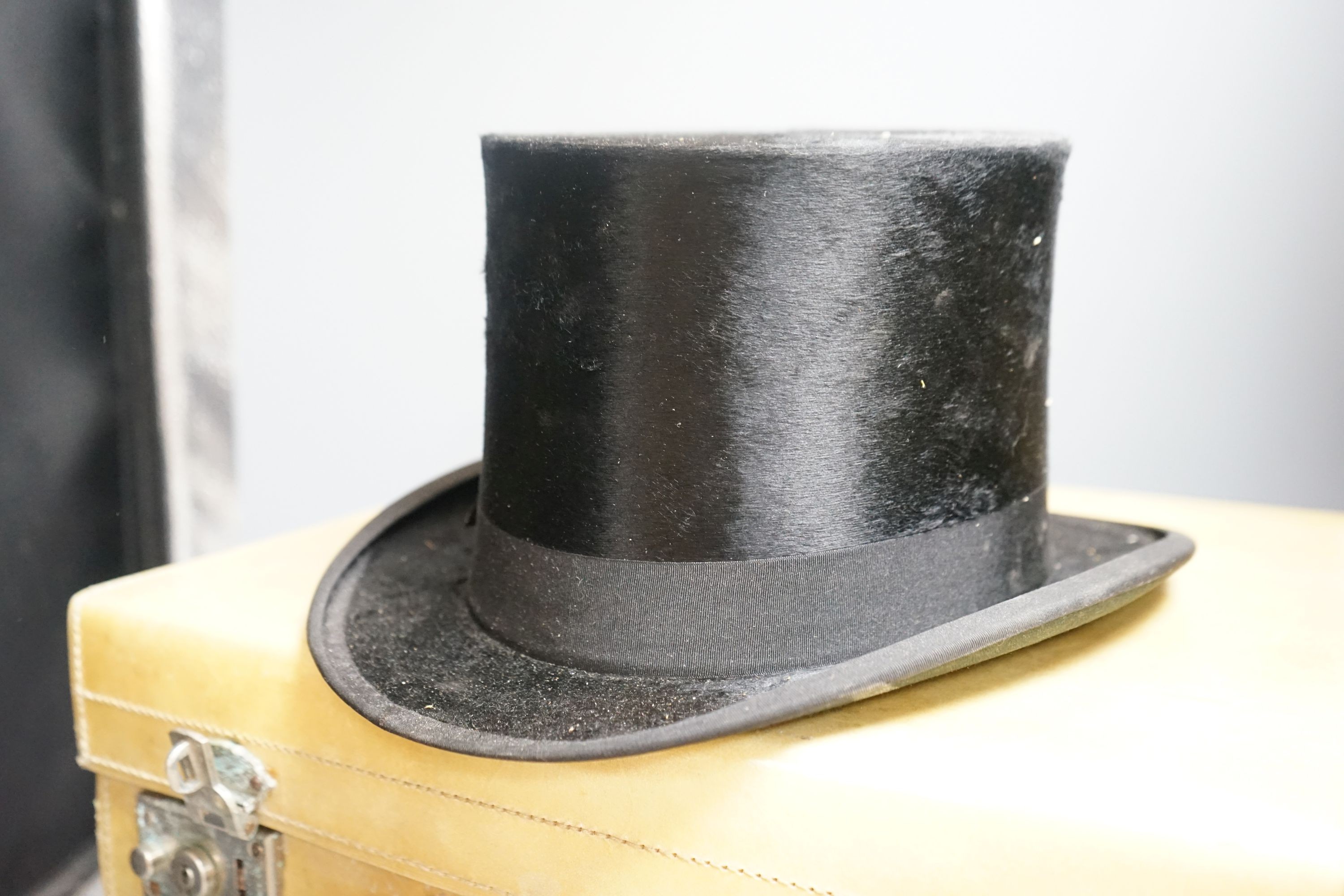 A top hat (boxed) and a cream vanity case